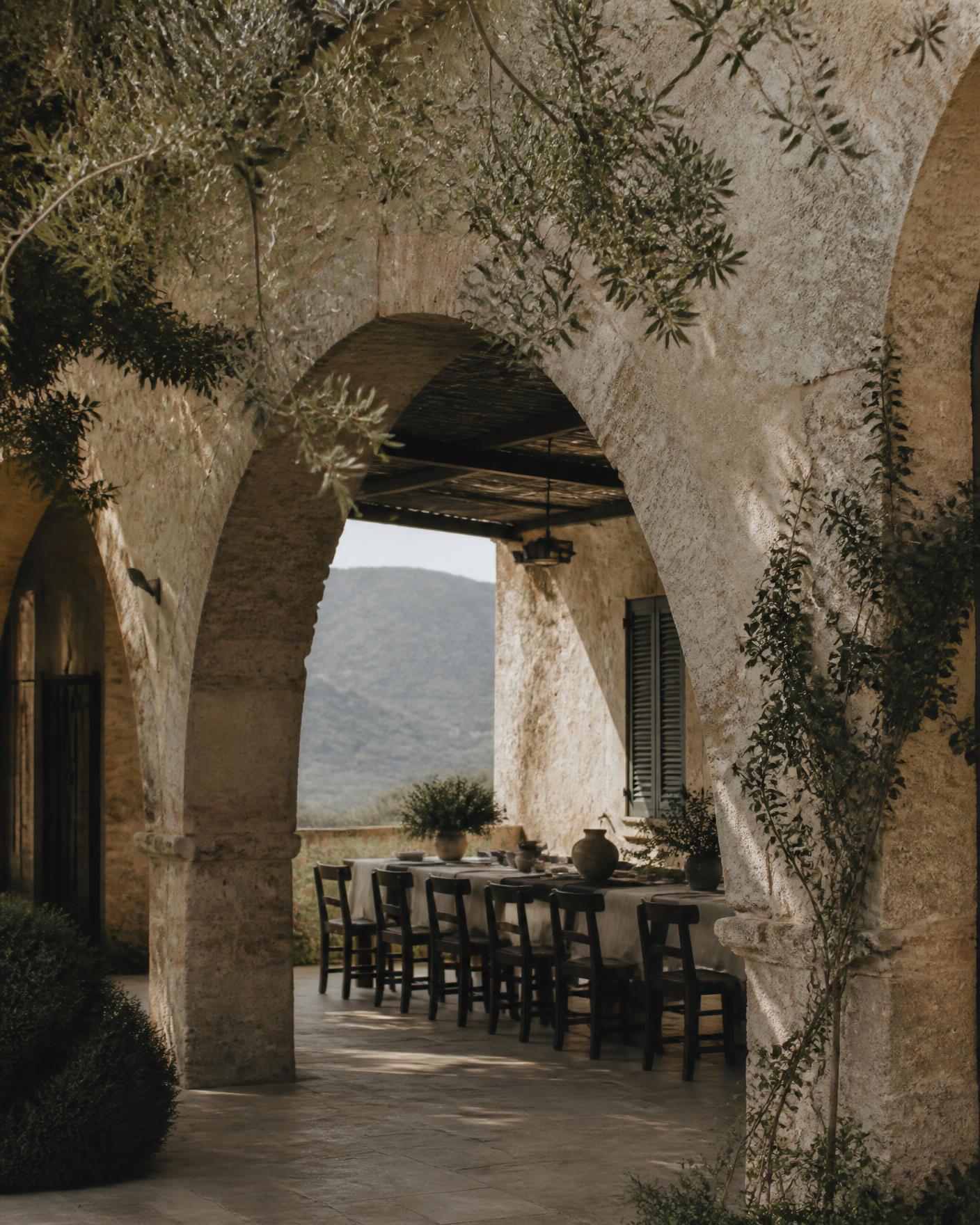 Shaded stone courtyard with arches and a long table set for dinner